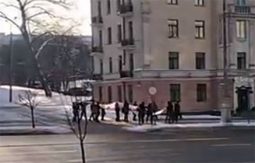 По центру Минска идет колонна людей с национальным флагом