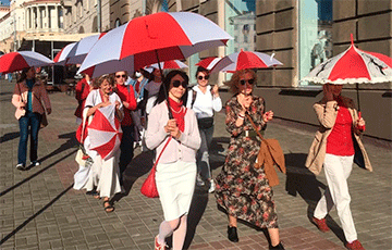 По проспекту Независимости идут девушки с бело-красно-белыми зонтами