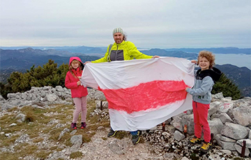 Как отец с детьми путешествует по горам с  бело-красно-белым флагом